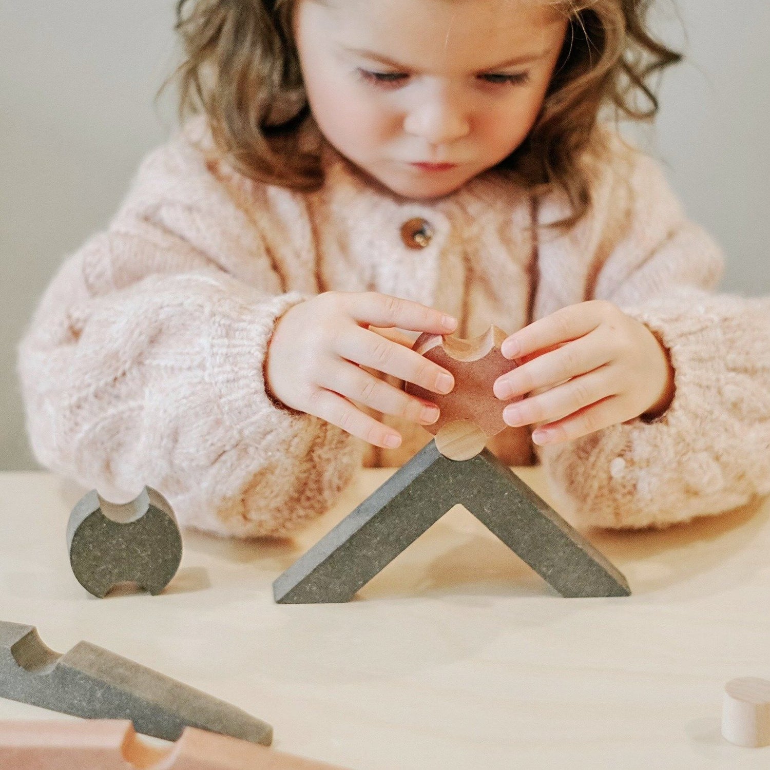 girl playing with wooden balancing blocks puzzle shapes